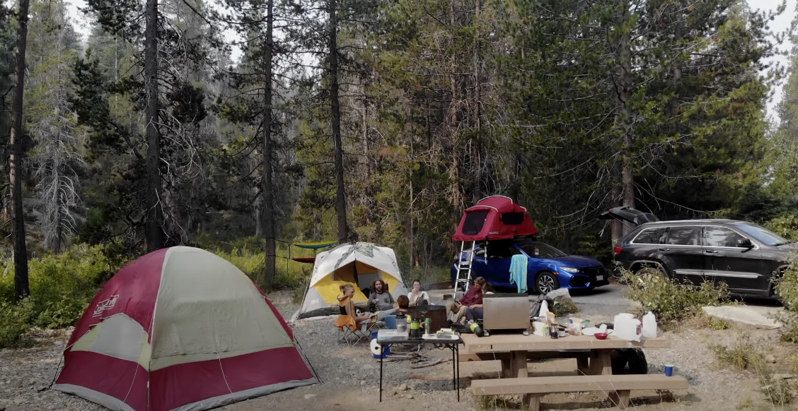 Photo of a group of friends camping in the forest, with tents and tables