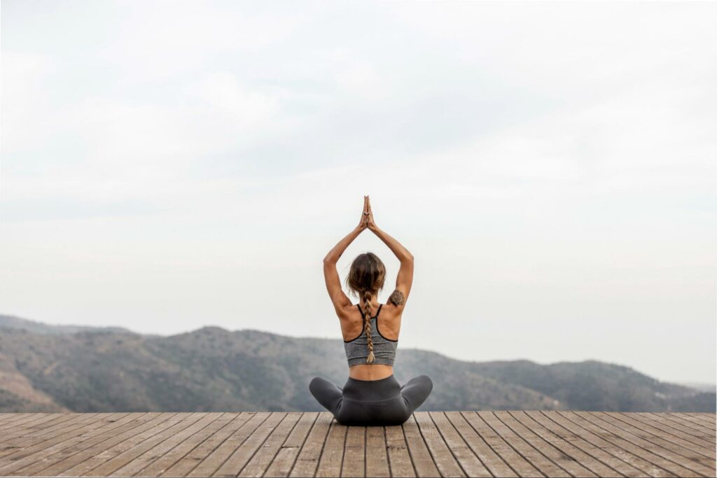 A woman practicing Yoga in front of the hills