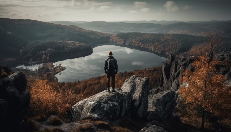 a man wearing a backpack standing on the edge of the mountain and enjoying solitude