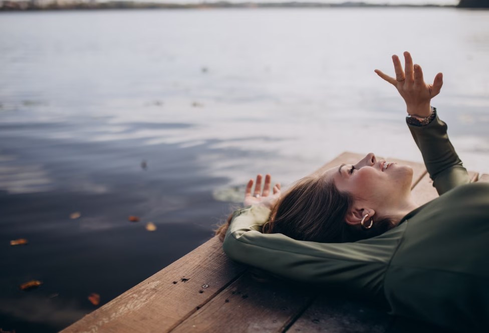 a young woman lying on a wooden berth by the lake