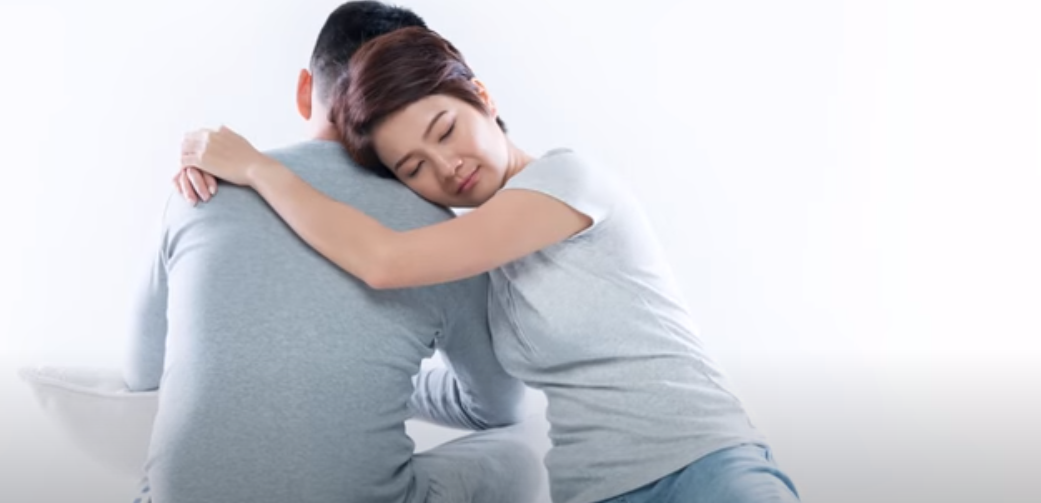 a woman sitting with her arms around a man, leaning on him